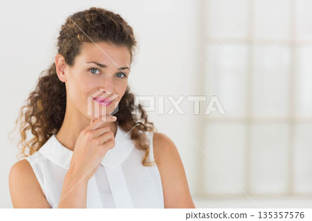 Woman wearing sleeveless blouse resting chin on hand gazing toward camera in studio window area Woman wearing sleeveless blouse resting chin on hand gazing toward camera in studio window area 135357576