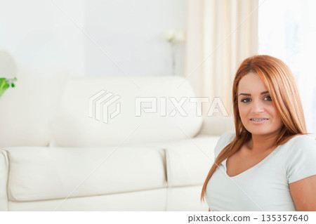 Woman sitting on pale leather sofa in living room with potted plant and vase, copy space Woman sitting on pale leather sofa in living room with potted plant and vase, copy space 135357640