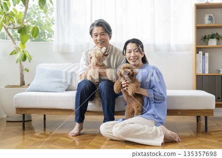 一對五十多歲的夫婦面帶笑容地看著鏡頭,他們的寵物狗也在其中——展現了與狗相伴的生活。 一對五十多歲的夫婦面帶笑容地看著鏡頭,他們的寵物狗也在其中——展現了與狗相伴的生活。 135357698