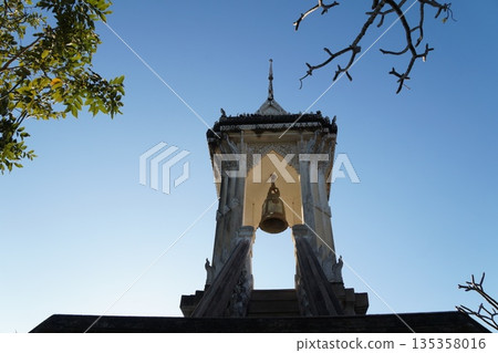 White towers of the temple against the backdrop of a blue sky and a blooming garden with trees.View of the temple towers. 135358016