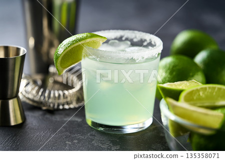 Classic lime margarita cocktail. Margarita cocktail on dark stone table, selective focus. Classic lime margarita cocktail. Margarita cocktail on dark stone table, selective focus. 135358071