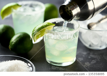 margarita cocktail is poured into a glass on a black background, selective focus. 135358095