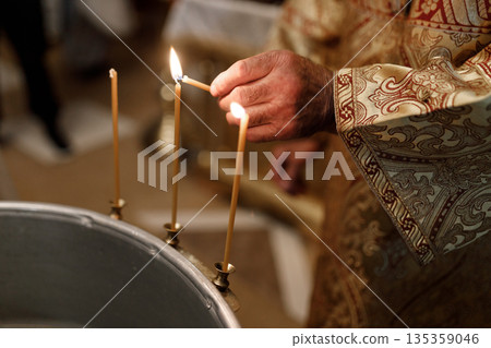 Orthodox Priest Lighting Candle During Child Baptism Orthodox Priest Lighting Candle During Child Baptism 135359046