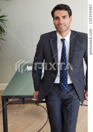 Businessman leaning on conference table with loose documents and potted plant in office, copy space Businessman leaning on conference table with loose documents and potted plant in office, copy space 135359367