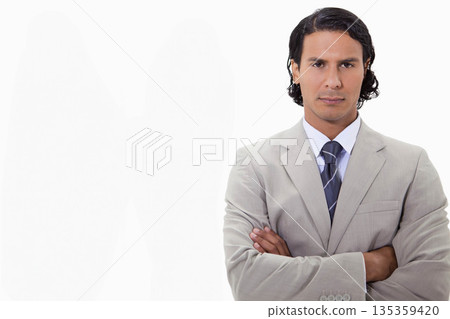 Man in 30s standing with crossed arms in studio wearing beige suit jacket, tie, copy space Man in 30s standing with crossed arms in studio wearing beige suit jacket, tie, copy space 135359420