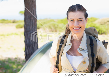 Woman standing at campsite with olive backpack by pitched tent and pine trunk, copy space Woman standing at campsite with olive backpack by pitched tent and pine trunk, copy space 135359449