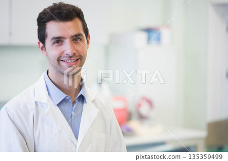 Male researcher wearing white lab coat standing in research laboratory with sharps container 135359499