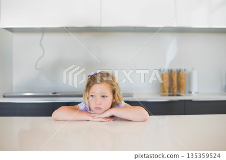 Female child leaning on quartz counter in kitchen, viewing cereal canisters beside stovetop cable 135359524