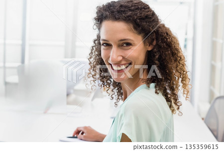 Female office worker sitting at desk tapping touchscreen in modern office, copy space 135359615
