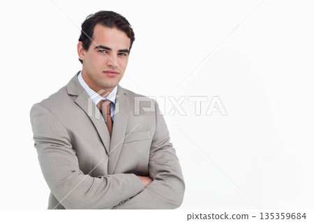 Male standing with arms crossed in studio wearing light gray suit and brown tie, copy space Male standing with arms crossed in studio wearing light gray suit and brown tie, copy space 135359684