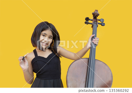 Passionate little Asian girl in black dress playing cello and shouting with joy. Concept for music education, child prodigy, emotional performance, and creative talent Passionate little Asian girl in black dress playing cello and shouting with joy. Concept for music education, child prodigy, emotional performance, and creative talent 135360292