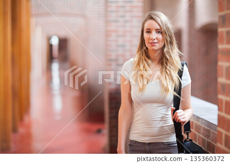 Woman leaning elbow on brick-lined corridor ledge by window carrying black shoulder bag, copy space 135360372