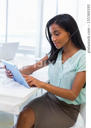African American woman reviewing charts and interacting with tablet at office desk, copy space 135360395