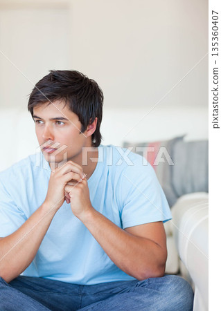White man leaning on light-colored sofa in living room with pillow, gazing right copy space White man leaning on light-colored sofa in living room with pillow, gazing right copy space 135360407