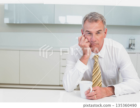 Middle-aged male wearing striped tie leaning on home kitchen counter holding white mug, copy space Middle-aged male wearing striped tie leaning on home kitchen counter holding white mug, copy space 135360490