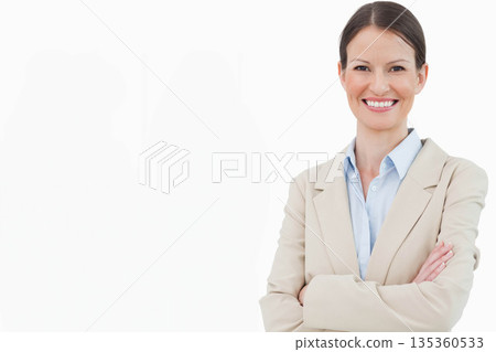 Businesswoman standing with arms crossed in studio wearing beige blazer and blue blouse, copy space Businesswoman standing with arms crossed in studio wearing beige blazer and blue blouse, copy space 135360533