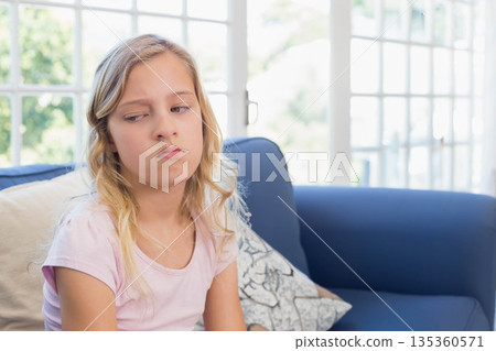 Girl sitting on blue sofa at home leaning on cushion gazing at glass-pane windows, copy space Girl sitting on blue sofa at home leaning on cushion gazing at glass-pane windows, copy space 135360571