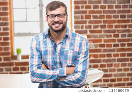 African American man standing in loft office by white desk holding colored pens and succulent 135360679