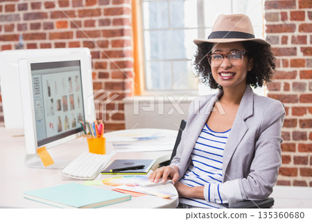 African American woman sitting in studio at desk with monitor holding color swatch book, copy space African American woman sitting in studio at desk with monitor holding color swatch book, copy space 135360680