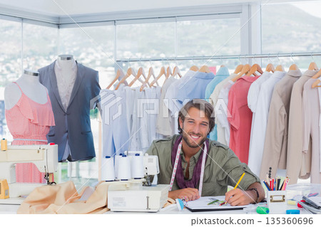 Male fashion designer sewing swatches at bright studio with sewing machines and mannequins 135360696