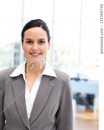 Professional woman wearing tailored blazer, standing in modern office with floor-to-ceiling windows Professional woman wearing tailored blazer, standing in modern office with floor-to-ceiling windows 135360748