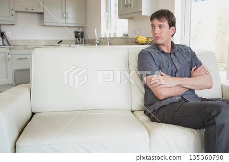 Man sitting on white leather sofa in kitchen beside granite countertop with fruit bowl, copy space Man sitting on white leather sofa in kitchen beside granite countertop with fruit bowl, copy space 135360790