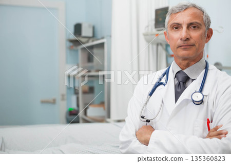 Senior male physician standing beside exam table at hospital exam room with stethoscope, copy space Senior male physician standing beside exam table at hospital exam room with stethoscope, copy space 135360823