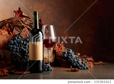 Bottle of red wine with blue grapes on a brown background. Bottle of red wine with blue grapes on a brown background. 135361021