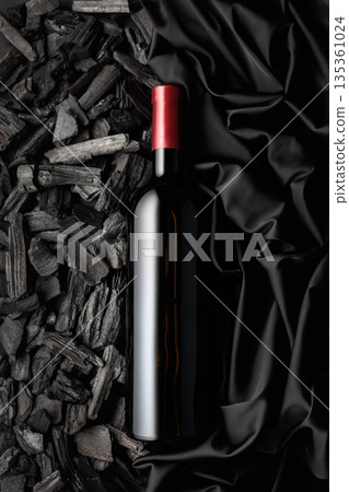 Bottle of red wine against a backdrop of charcoal and black satin. Bottle of red wine against a backdrop of charcoal and black satin. 135361024