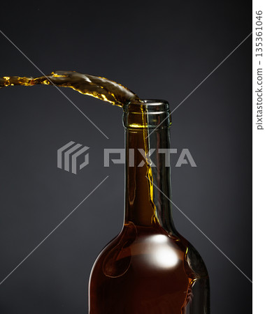 White wine of a rich amber color pours out of the bottle. White wine of a rich amber color pours out of the bottle. 135361046