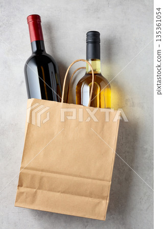 Bottles of red and white wine in a paper bag on a white marble background. Bottles of red and white wine in a paper bag on a white marble background. 135361054