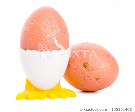 Unique pink eggs on a yellow egg cup with one egg beside it on a white background Unique pink eggs on a yellow egg cup with one egg beside it on a white background 135361468