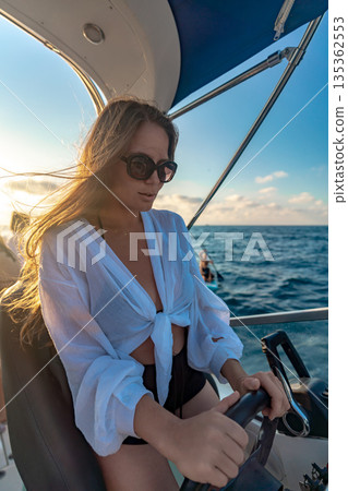 Woman, boating, ocean, a young female driving a boat enjoying a bright summer day with golden light 135362553