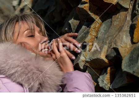 Woman Winter Rock Touching Affectionate outdoor portrait, woman caressing rock formation, cold weather. 135362651