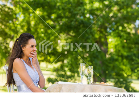 Woman smiling sitting in garden at round table with bubbly drinks and appetizers, copy space Woman smiling sitting in garden at round table with bubbly drinks and appetizers, copy space 135362695