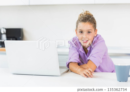 Girl working on silver laptop at kitchen counter near black coffee machine, copy space Girl working on silver laptop at kitchen counter near black coffee machine, copy space 135362734