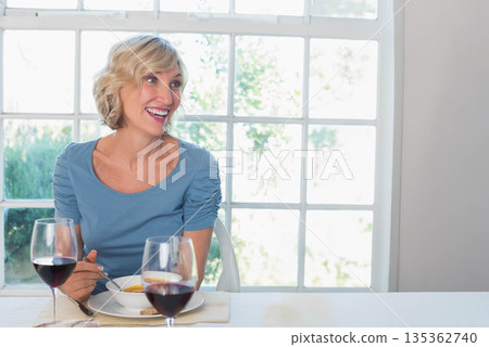 Middle-aged woman smiling while holding spoon over soup bowl with wine glasses at dining table Middle-aged woman smiling while holding spoon over soup bowl with wine glasses at dining table 135362740
