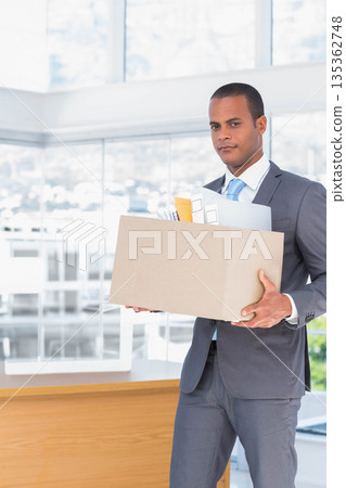 African American man wearing suit holding box of office supplies at reception desk, copy space 135362748