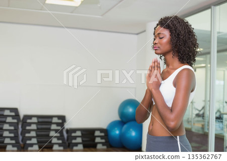 African American woman standing practicing meditation in gym with steps, exercise balls, copy space African American woman standing practicing meditation in gym with steps, exercise balls, copy space 135362767