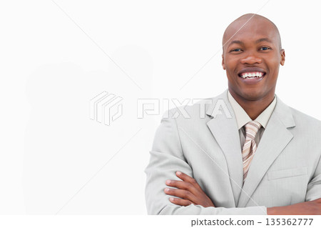 African American man crossing arms in studio wearing gray suit and striped tie, copy space 135362777