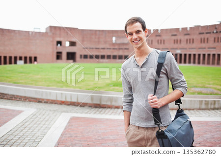 Male student standing by low brick wall on university quadrangle carrying messenger bag, copy space Male student standing by low brick wall on university quadrangle carrying messenger bag, copy space 135362780