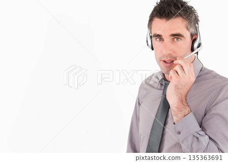 Man in his thirties answering calls in office wearing collared shirt tie and headset, copy space Man in his thirties answering calls in office wearing collared shirt tie and headset, copy space 135363691