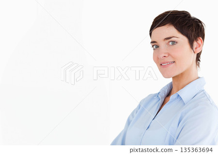 Mid adult woman standing with arms folded in studio wearing light blue shirt, copy space 135363694