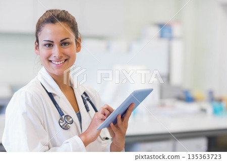 Female doctor holding tablet while reviewing data in clinical office with stethoscope, copy space 135363723