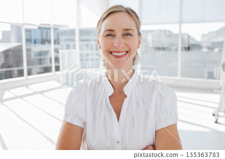 Mature adult woman in white blouse standing by office window showing sunlight reflections on floor Mature adult woman in white blouse standing by office window showing sunlight reflections on floor 135363783