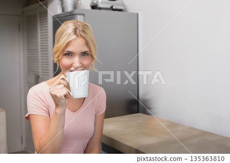 Female drinking from white ceramic mug at kitchen counter with grey fridge, copy space Female drinking from white ceramic mug at kitchen counter with grey fridge, copy space 135363810