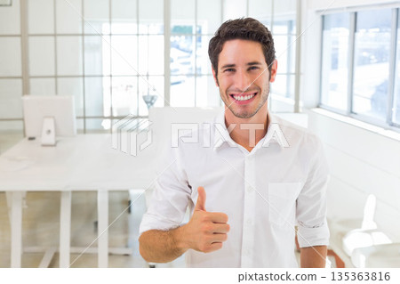 Man standing and smiling in bright modern office with white desk computer monitor glass partition 135363816