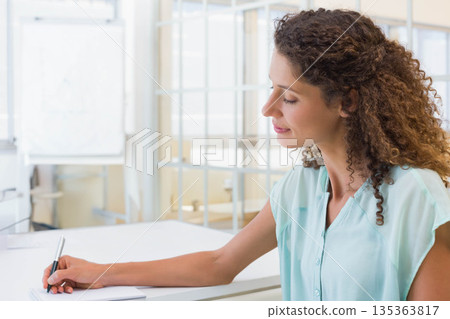 Female office worker writing notes on paper with pen by whiteboard, glass partition, copy space Female office worker writing notes on paper with pen by whiteboard, glass partition, copy space 135363817