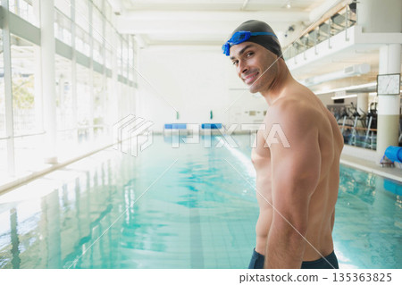 Male swimmer standing by pool lanes in aquatic center wearing swim cap, goggles, copy space Male swimmer standing by pool lanes in aquatic center wearing swim cap, goggles, copy space 135363825