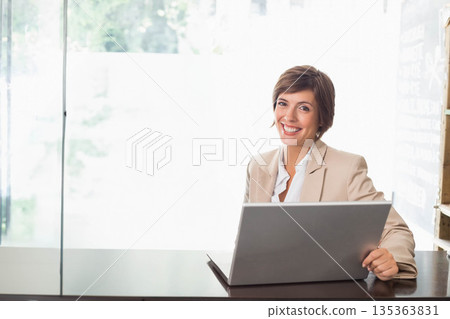 Female professional sitting at desk typing on laptop with chalkboard wall in office, copy space 135363831